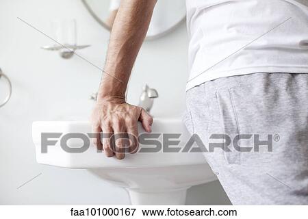 Stock Photo - Man leaning against bathroom sink. Fotosearch