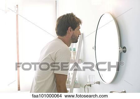 Man looking at self in bathroom mirror View Large Photo Image Picture - Man looking at self in bathroom mirror. Fotosearch
