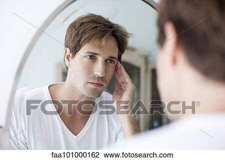 Man looking at self in mirror with concerned look View Large Photo Image Stock Image - Man looking at self in mirror with concerned look. Fotosearch