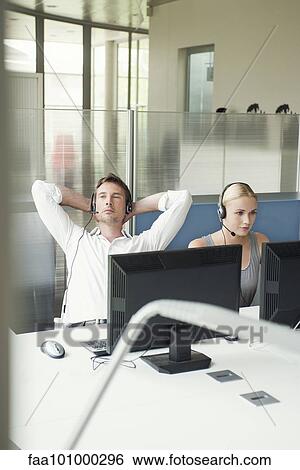 Stock Photograph - Man relaxing with arms behind head at work. Fotosearch
