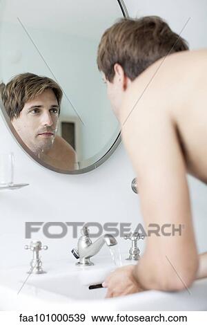 Man washing face in bathroom sink looking at self in mirror View Large Photo Image Stock Photo - Man washing face in bathroom sink looking at self in mirror. Fotosearch