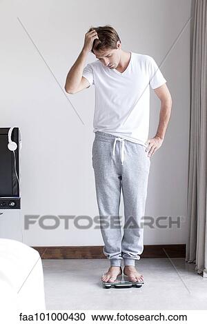 Man weighing self on bathroom scale View Large Photo Image Stock Image - Man weighing self on bathroom scale. Fotosearch