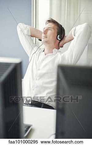 Stock Photography - Man with arms behind head relaxing at work. Fotosearch