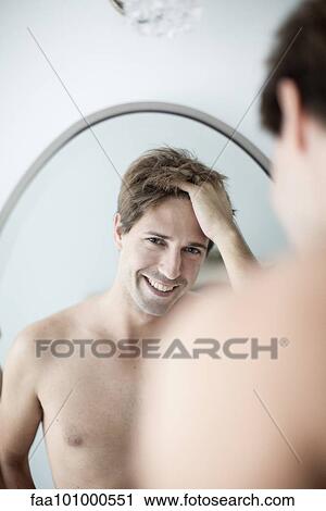 Man with hands in hair looking at self in mirror with look of amusement View Large Photo Image Stock Image - Man with hands in hair looking at self in mirror with look of amusement. Fotosearch