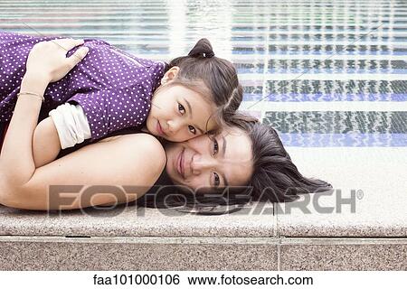 "Mother and daughter lying together on edge of fountain, portrait" View Large Photo Image Stock Photograph - "Mother and daughter lying together on edge of fountain, portrait". Fotosearch