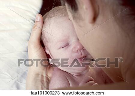 Stock Image - "Mother bonding with newborn baby, over the shoulder view". Fotosearch