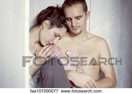 Stock Photo - New parents sitting with newborn baby. Fotosearch