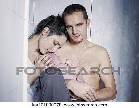 Stock Photo - New parents sitting with newborn baby. Fotosearch