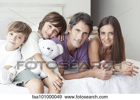 "Parents and young sons relaxing together on bed, portrait" View Large Photo Image Stock Photo - "Parents and young sons relaxing together on bed, portrait". Fotosearch