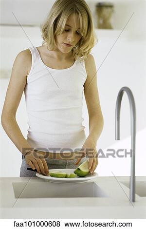Teenage girl standing at counter slicing apple View Large Photo Image Stock Photo - Teenage girl standing at counter slicing apple. Fotosearch