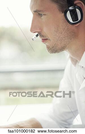 Telemarketer wearing phone headset at work View Large Photo Image Stock Image - Telemarketer wearing phone headset at work. Fotosearch