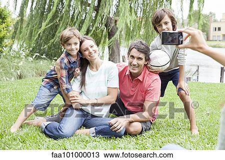 Stock Image - "Using digital camera to photograph family with two children, personal perspective". Fotosearch