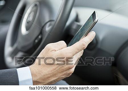 Using smartphone while driving View Large Photo Image Stock Photo - Using smartphone while driving. Fotosearch