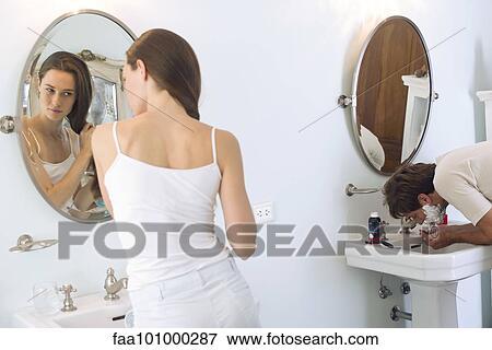 Stock Photo - "Woman brushing hair, husband shaving". Fotosearch