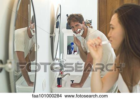 "Woman brushing teeth, husband shaving" View Large Photo Image Picture - "Woman brushing teeth, husband shaving". Fotosearch