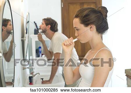 "Woman brushing teeth, husband shaving" View Large Photo Image Stock Photography - "Woman brushing teeth, husband shaving". Fotosearch