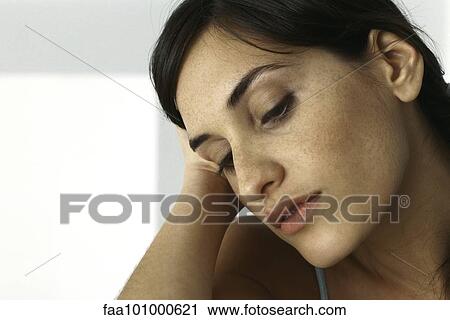 Stock Image - "Woman holding head, looking down, portrait". Fotosearch