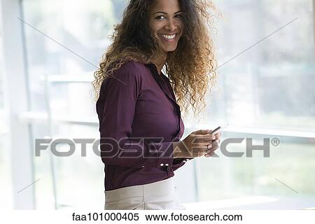 Stock Photography - "Woman holding smartphone, smiling, portrait". Fotosearch