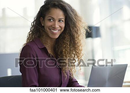 Stock Image - "Woman using laptop computer, smiling". Fotosearch