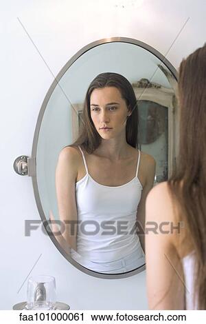 Stock Image - Woman's reflection in bathroom mirror. Fotosearch