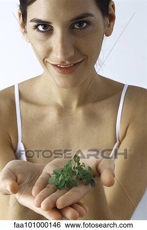 Stock Photograph - "Young woman holding handful of fresh thyme, smiling at camera". Fotosearch