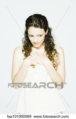"Young woman holding hands over heart, looking away" View Large Photo Image Stock Photo - "Young woman holding hands over heart, looking away". Fotosearch