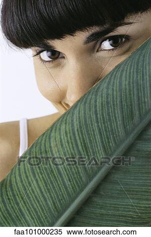 Stock Photography - "Young woman holding leaf in front of face, portrait". Fotosearch
