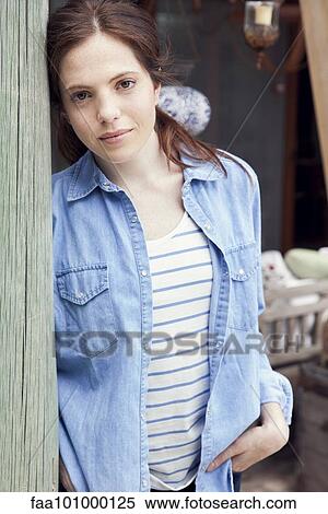 "Young woman leaning against wooden post, portrait" View Large Photo Image Stock Photography - "Young woman leaning against wooden post, portrait". Fotosearch