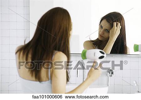 "Young woman looking in mirror, drying hair" View Large Photo Image Stock Photograph - "Young woman looking in mirror, drying hair". Fotosearch