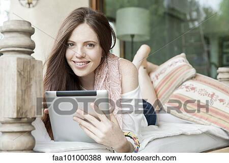 "Young woman lying on stomach with digital tablet, portrait" View Large Photo Image Stock Photo - "Young woman lying on stomach with digital tablet, portrait". Fotosearch