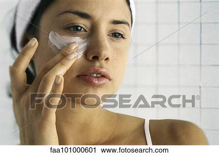 Stock Image - "Young woman moisturizing face, close-up". Fotosearch