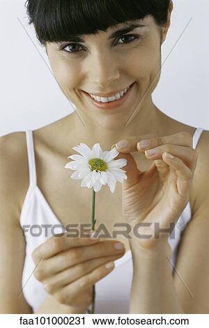 "Young woman plucking petals from flower, smiling, portrait" View Large Photo Image Stock Image - "Young woman plucking petals from flower, smiling, portrait". Fotosearch