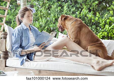 "Young woman sitting beside dog outdoors, reading book" View Large Photo Image Picture - "Young woman sitting beside dog outdoors, reading book". Fotosearch