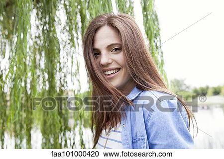 Stock Image - "Young woman smiling outdoors, portrait". Fotosearch
