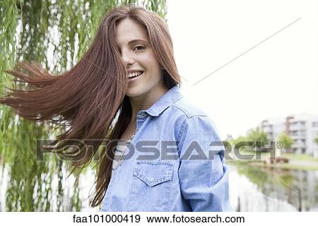 Young woman tossing her hair outdoors View Large Photo Image Stock Photo - Young woman tossing her hair outdoors. Fotosearch
