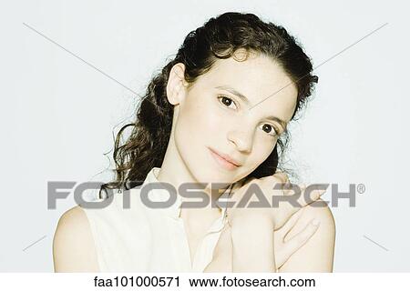 Stock Image - "Young woman touching shoulder, smiling at camera, portrait". Fotosearch