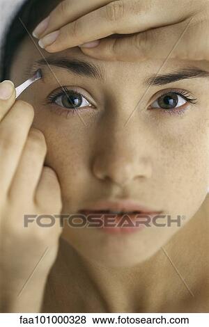 Stock Photo - "Young woman tweezing eyebrows, close-up". Fotosearch