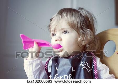 Stock Image - Baby girl feeding herself. Fotosearch