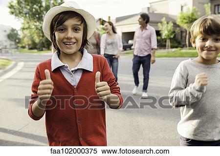 Stock Photography - "Boys playing outdoors, family in background". Fotosearch