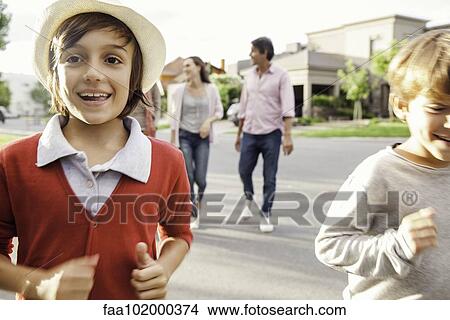 "Boys running in street, family walking behind them" View Large Photo Image Picture - "Boys running in street, family walking behind them". Fotosearch