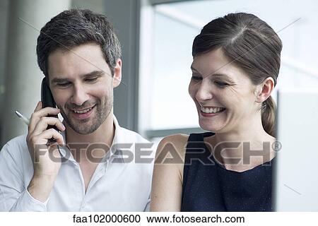 "Business colleagues smiling together, man talking on cell phone" View Large Photo Image Stock Image - "Business colleagues smiling together, man talking on cell phone". Fotosearch