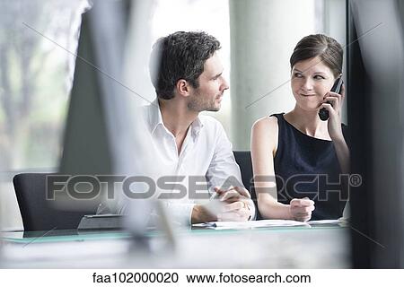 Stock Image - Businessman listening to associates phone call. Fotosearch
