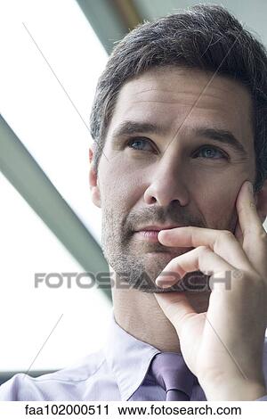 Stock Image - "Businessman looking up in thought, portrait". Fotosearch