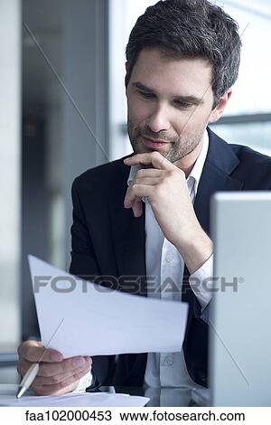 Stock Image - Businessman reading document. Fotosearch