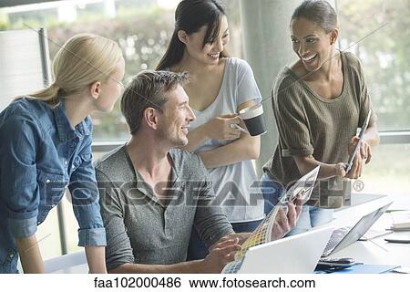 Stock Photograph - Colleagues having lighthearted moment at work. Fotosearch