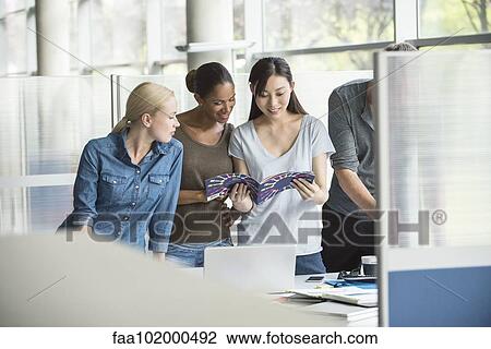 Colleagues looking through catalog together View Large Photo Image Stock Image - Colleagues looking through catalog together. Fotosearch