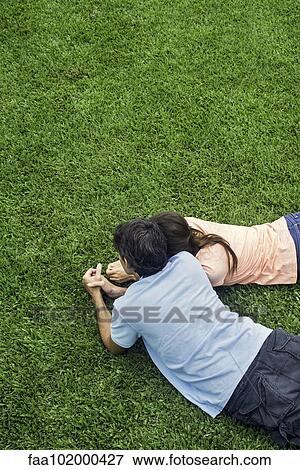Stock Photo - Couple lying together on grass. Fotosearch