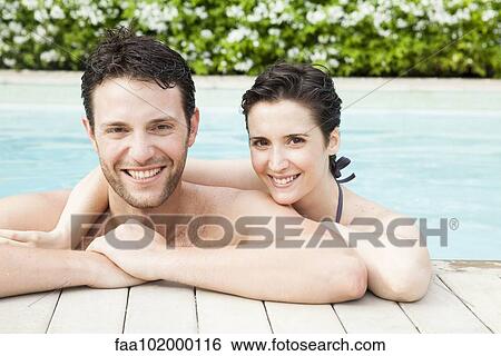 Stock Photograph - "Couple relaxing together in pool, portrait". Fotosearch
