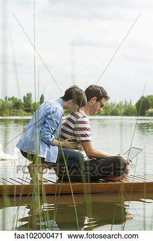 Couple using laptop computer on dock View Large Photo Image Stock Image - Couple using laptop computer on dock. Fotosearch