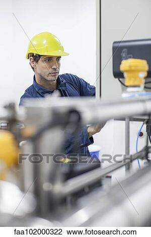 Stock Image - Factory worker operating industrial equipment. Fotosearch